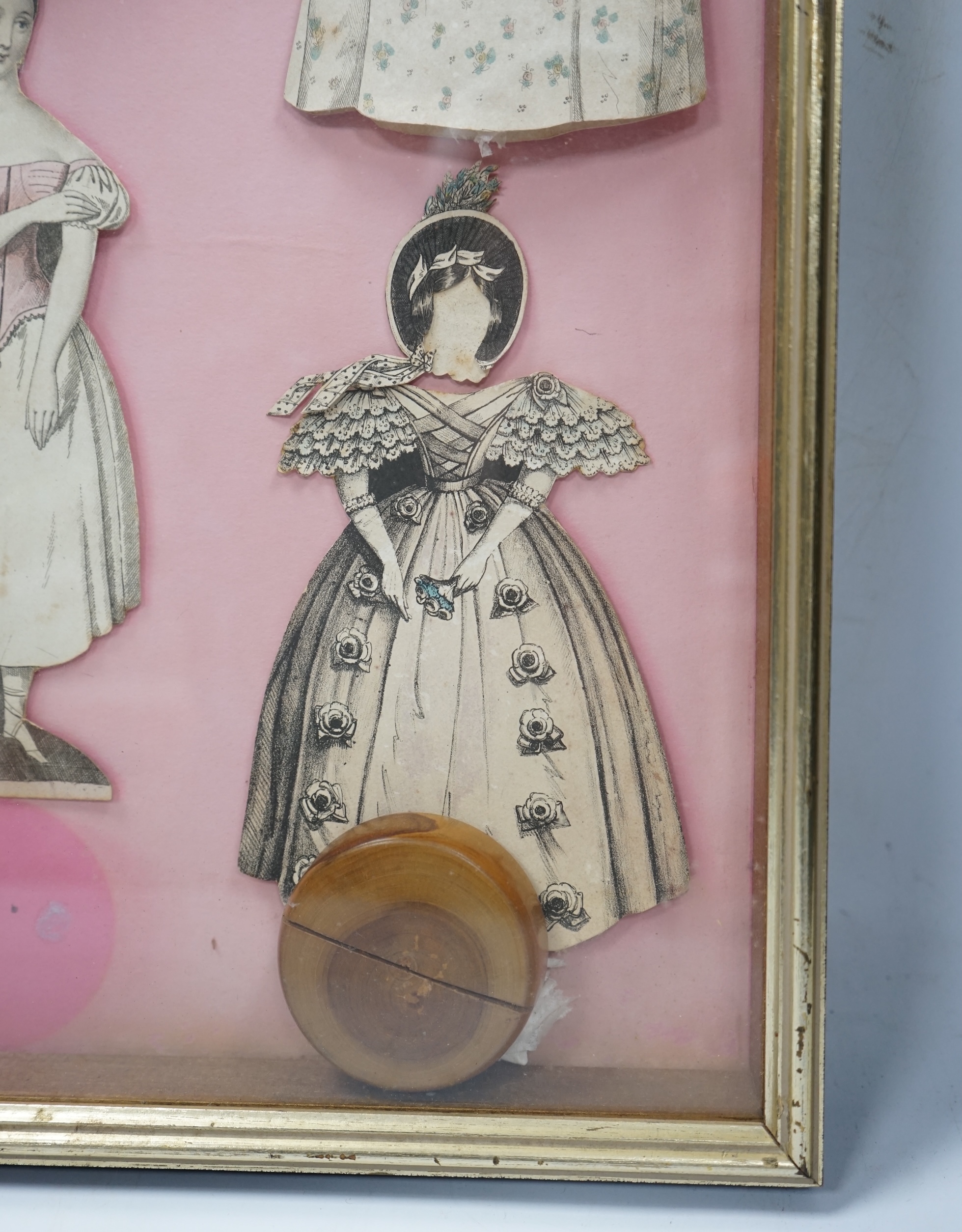 An early 19th century framed Rudolph Ackermann La Poupee-Modele paper doll set, comprising of a double sided doll in lingerie with wooden stand, five double sided gowns and five bonnets, dimensions of the frame; 40cm wid